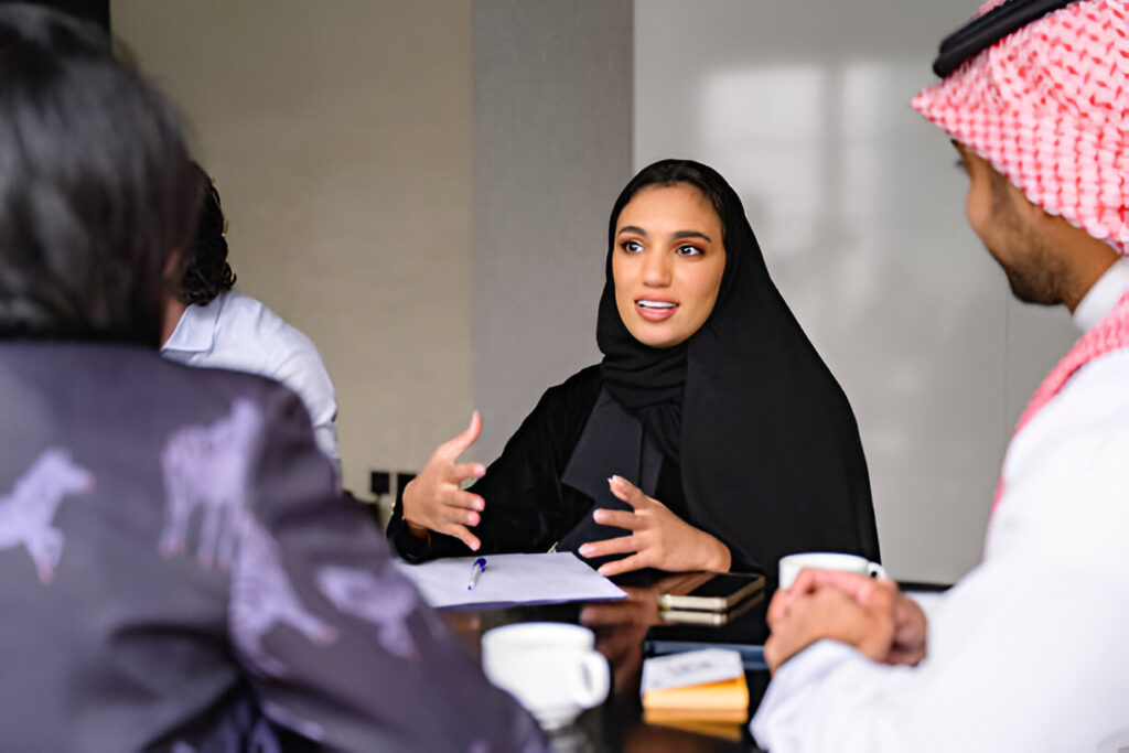 A Saudi woman engaging in a discussion with her colleagues at Kwader, focusing on catering services.